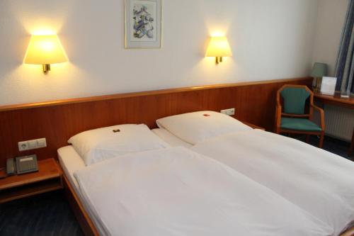 a bedroom with two beds and a chair and lights at Hotel Sonne in Leinfelden-Echterdingen