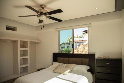 a bedroom with a ceiling fan and a bed with a window at Makari Vallarta in Puerto Vallarta