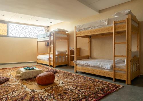a room with three bunk beds and a rug at surf house Agadir in Tama ou Ennza