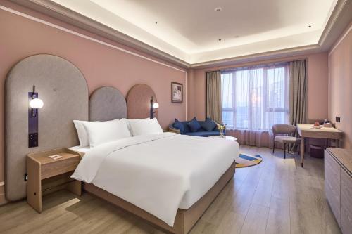 a bedroom with a large white bed and a desk at Mercure Yiwu International Trade City in Yiwu