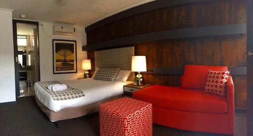 a bedroom with a bed and a red chair at Brougham Arms Hotel in Bendigo