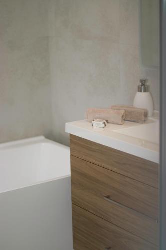 a bathroom with a sink and a bath tub at Salty Breeze Beach House in Orewa