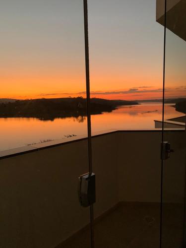 a view of a sunset from a room with a view of the water at Lagamar Hotel Varginha in Varginha