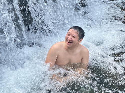 a man in the water in front of a waterfall at Zhangjiajie Highlights Guesthouse in Zhangjiajie