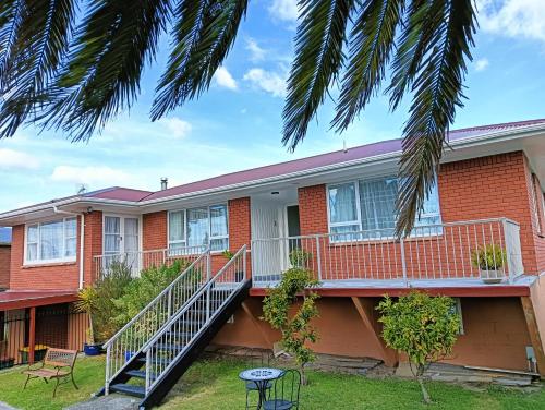 a red brick house with a porch and stairs at Steam Land Stay in Rotorua