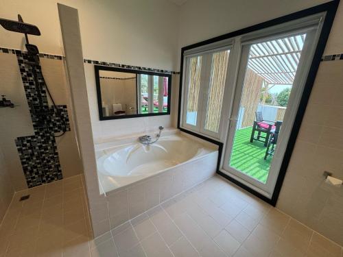 a large bathroom with a tub and a window at Ao Thai Resort in Sathing Phra