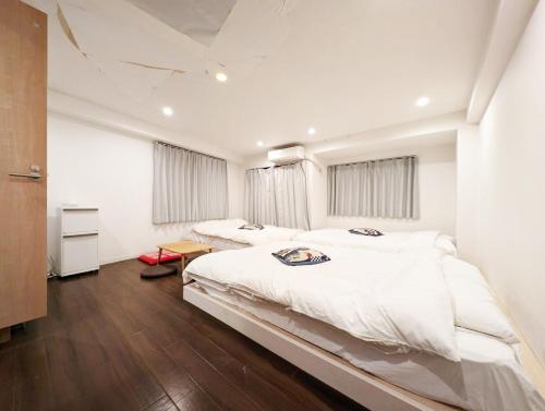 2 camas en un dormitorio con paredes blancas y suelo de madera en ホテル隅田川, en Tokio