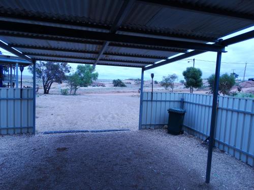 an empty building with a trash can in a field at Di's Dugouts in Coober Pedy