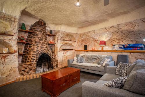 a living room with a stone wall with a fireplace at Di's Dugouts in Coober Pedy