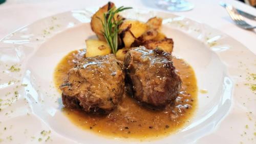 a plate of food with meat and potatoes on a table at Hotel Mediterraneo in Lignano Sabbiadoro
