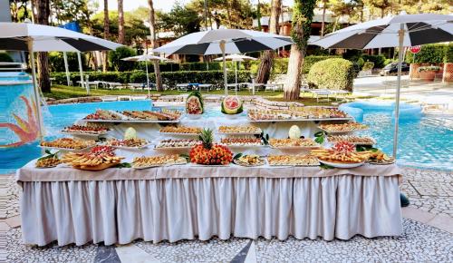 a buffet of food on a table next to a pool at Hotel Mediterraneo in Lignano Sabbiadoro