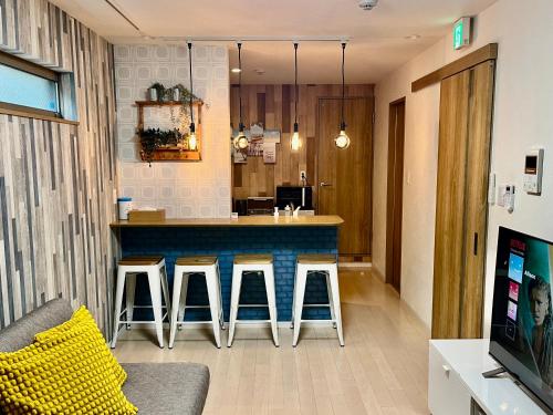 a living room with a bar with stools at 京セラドーム大正駅徒歩3分 USJ 大阪観光に便利 CityMaisonDomeFront in Osaka