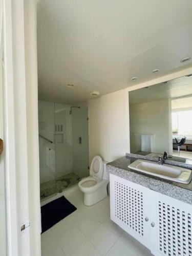 a white bathroom with a toilet and a sink at Bonito Loft in Ixtapa