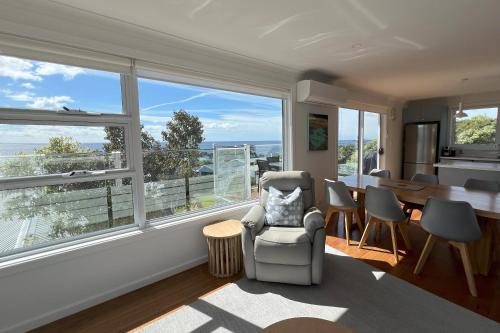 a living room with large windows and a table and chairs at TOP DECK - Panoramic water views of the Bay of Fires in Binalong Bay