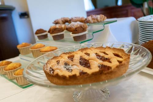 a cake on a glass plate on a table with cupcakes at Hotel Cala Del Porto in Vibo Valentia Marina