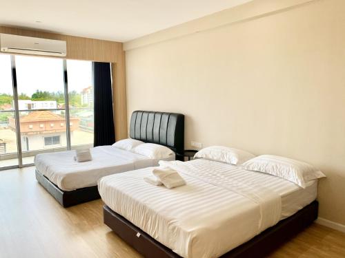 two beds in a room with a large window at Deco Home @ Aru Suites in Kota Kinabalu