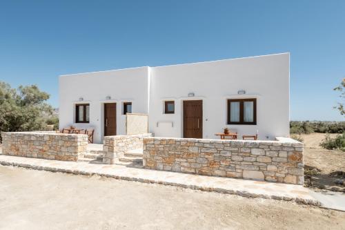 a white house with a stone wall at Naxian Air in Agios Georgios