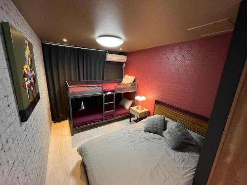 a bedroom with a bed with a red wall at 京セラドーム大正駅徒歩3分 USJ 大阪観光に便利 CityMaisonDomeFront in Osaka