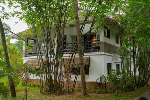 a white house with a balcony in the middle of trees at Malabar Ocean Front Resort And Spa, Bekal in Nīleshwar