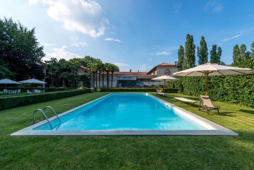 een zwembad in een tuin met een parasol bij Agriturismo Il Torrione in Pinerolo