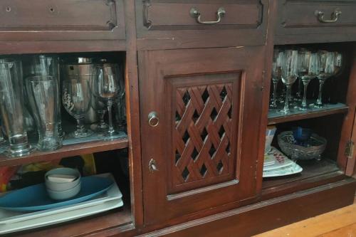 a wooden cabinet with wine glasses in it at The Oaks- a beautifully appointed 1890s villa in Featherston
