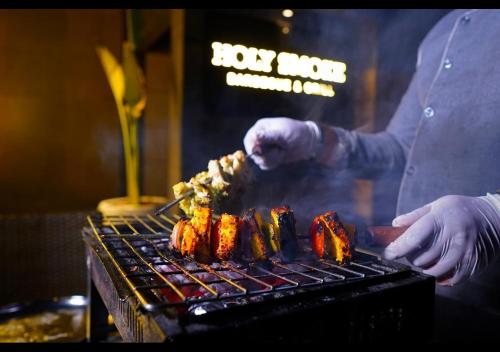 a man is cooking food on a grill at Hudson Resorts in Sriperumbudur