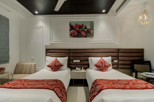 a hotel room with two beds with red pillows at Iris Park Hotel New Delhi in New Delhi