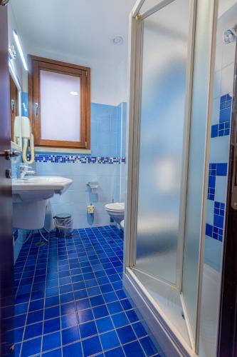 a blue tiled bathroom with a shower and a sink at Hotel Cala Del Porto in Vibo Valentia Marina