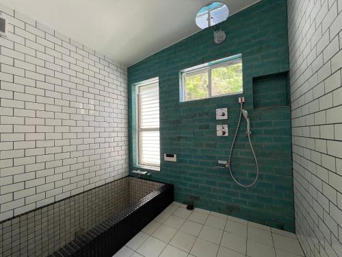 y baño con ducha de azulejos verdes y blancos. en ケーブキャビン シービュー BBQ ピザ サウナ ホットタブ - Cave Cabin Chiba Seaview BBQ Pizza Sauna Hot-tub, en Kobama