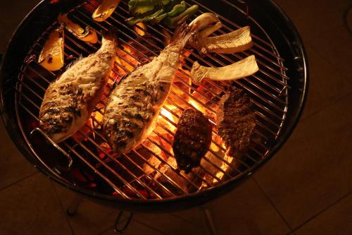 Una parrilla con pescado y otros alimentos. en ケーブキャビン シービュー BBQ ピザ サウナ ホットタブ - Cave Cabin Chiba Seaview BBQ Pizza Sauna Hot-tub, en Kobama