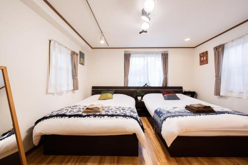 two beds in a room with white walls and windows at 50, Nakano 1, Entire house for rent, 中野1丁目 in Tokyo