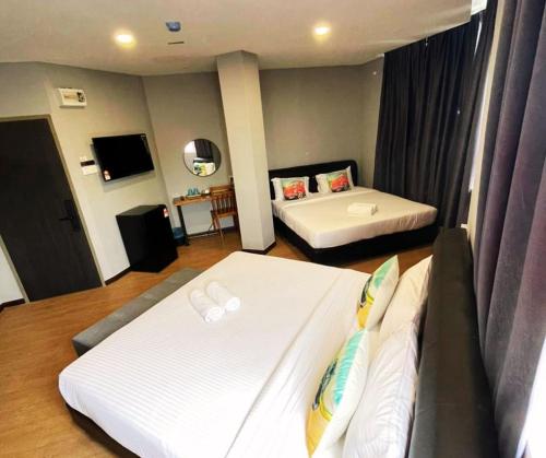 a hotel room with two beds and a television at RNK BoutiQue HOTEL in Jitra