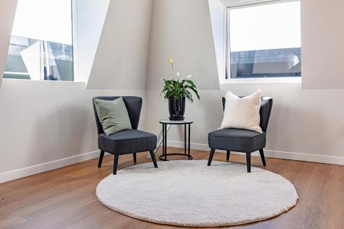 two chairs and a table with a potted plant in a room at Johnston Apartments - Award-winning building, Your unforgettable stay in Whanganui