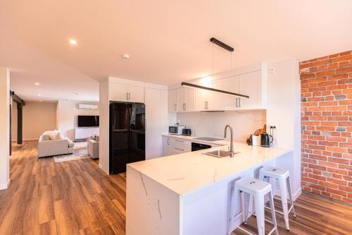 a kitchen with white cabinets and a brick wall at Johnston Apartments - Award-winning building, Your unforgettable stay in Whanganui