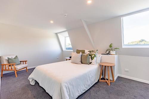 a white bedroom with a bed and a window at Johnston Apartments - Award-winning building, Your unforgettable stay in Whanganui