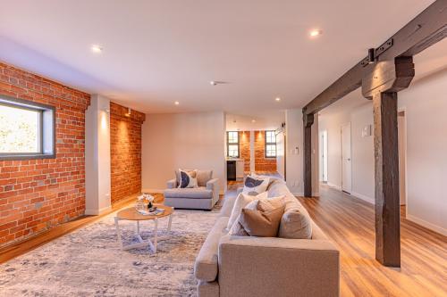 a living room with a couch and a brick wall at Johnston Apartments - Award-winning building, Your unforgettable stay in Whanganui