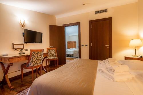 a hotel room with a bed and a desk and a television at Hotel Cala Del Porto in Vibo Valentia Marina