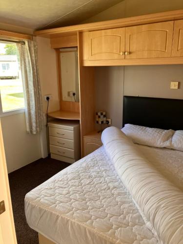 a bedroom with a large white bed and a window at Lazeeedays on Mersea Island in Colchester