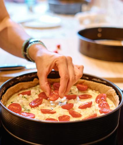 a person is putting pepperoni on top of a pie at Engelwirt Hotel & Apartments in Berching