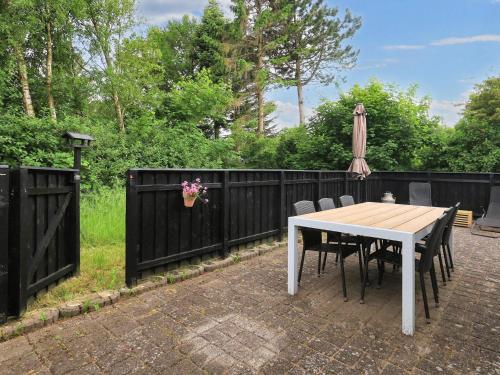 a table with chairs and an umbrella next to a fence at 4 person holiday home in Fjerritslev-By Traum in Fjerritslev