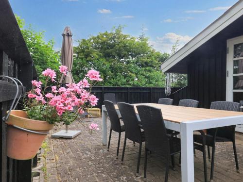 a patio with a table and chairs and pink flowers at 4 person holiday home in Fjerritslev-By Traum in Fjerritslev