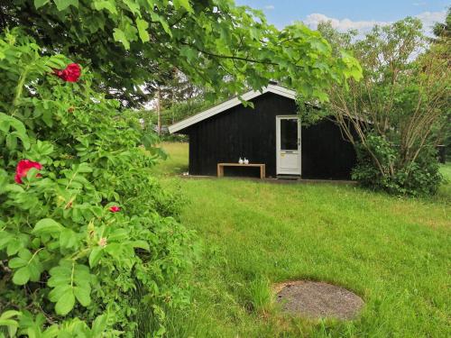 a black shed with a dog sitting on a bench in a yard at 4 person holiday home in Fjerritslev-By Traum in Fjerritslev