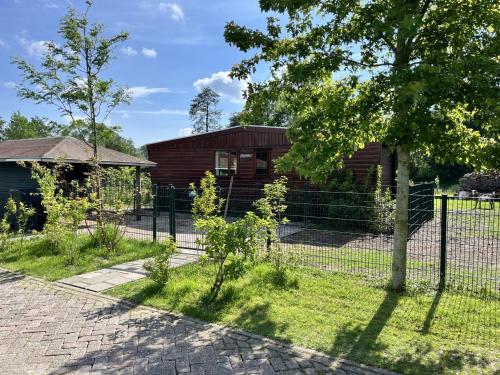 a fence in front of a small house at Vrijstaand chalet met veel buitenruimte en veranda in Zuid-Scharwoude