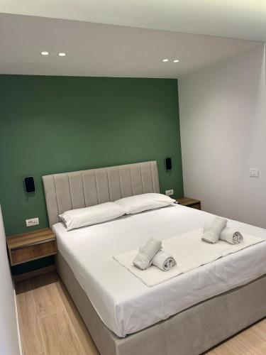 a bedroom with a large white bed with a green wall at Emily’s Hotel in Himare