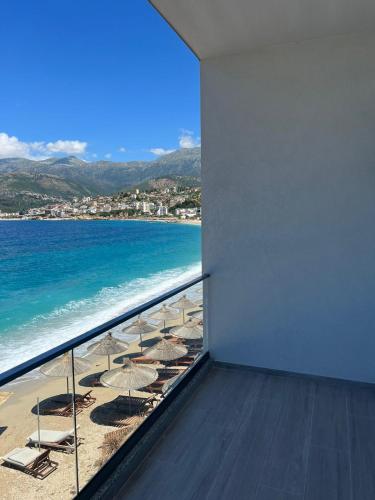a balcony with chairs and umbrellas on a beach at Emily’s Hotel in Himare