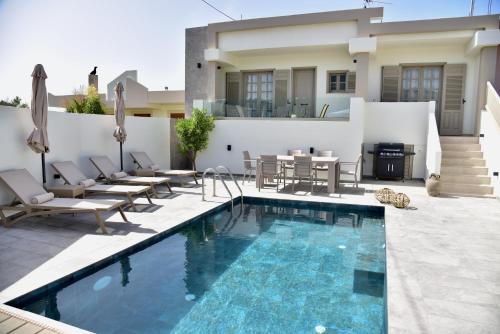 a swimming pool with chairs and a house at Melia Casa in Rhodes Town