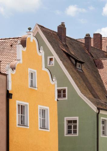 a yellow and green house with white windows at Engelwirt Hotel & Apartments in Berching