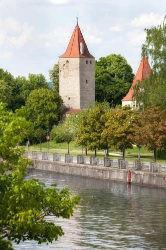 a building with a clock tower next to a river at Engelwirt Hotel & Apartments in Berching