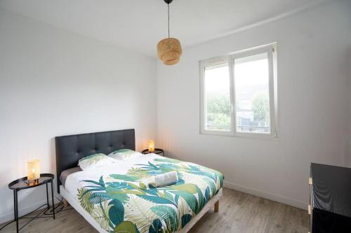 une chambre avec un lit avec un couvre-lit tropical et une fenêtre dans l'établissement Appartement T3 avec jardin, à Lanester