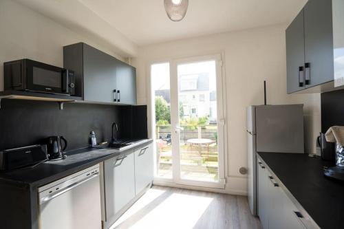 une cuisine avec des appareils électroménagers noirs et blancs et une porte coulissante en verre dans l'établissement Appartement T3 avec jardin, à Lanester